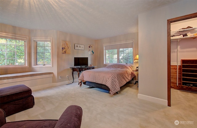 carpeted bedroom with a textured ceiling, a closet, and a walk in closet