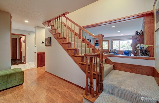 staircase with wood-type flooring and a textured ceiling