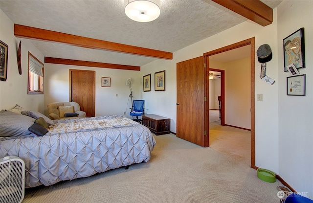 bedroom with a textured ceiling, light carpet, and beamed ceiling