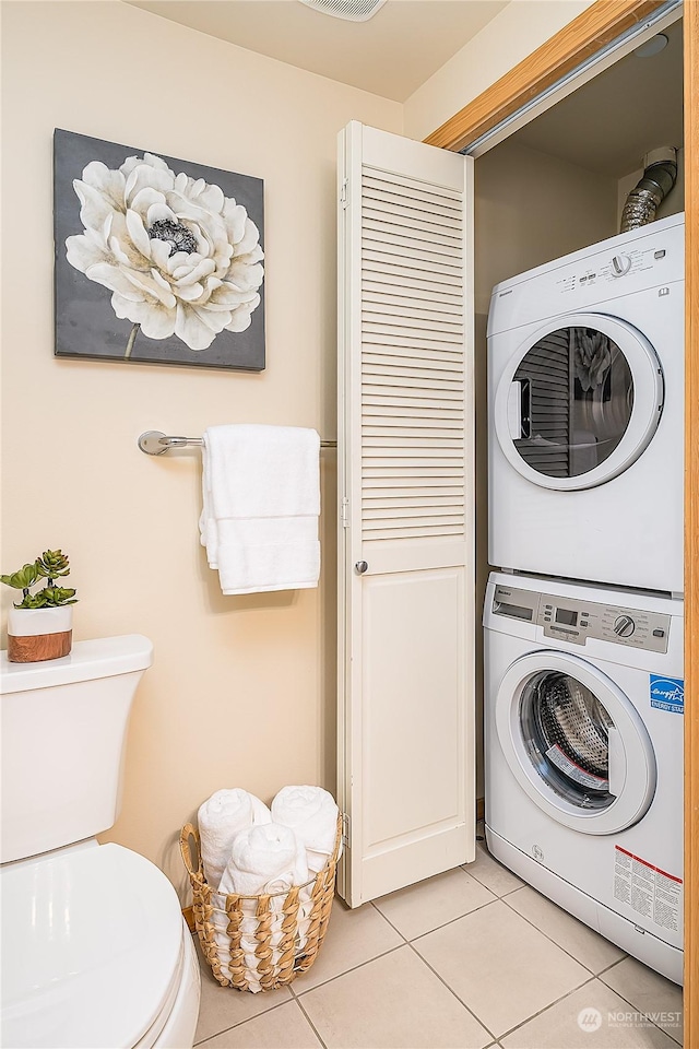 clothes washing area featuring stacked washer and dryer and light tile patterned flooring