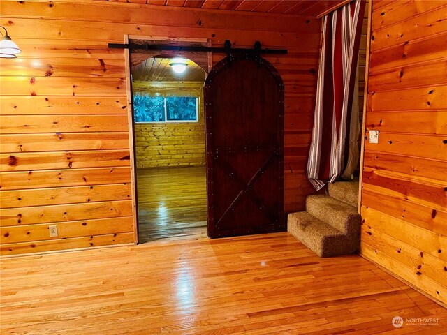 interior space with light wood-type flooring, wood walls, and a barn door