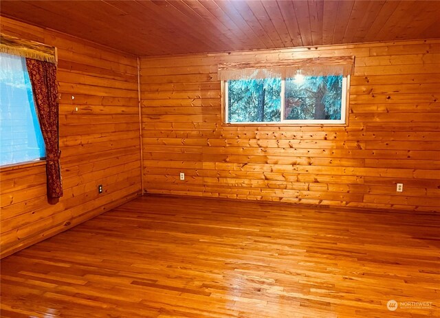 empty room featuring wooden walls, light hardwood / wood-style floors, and wooden ceiling