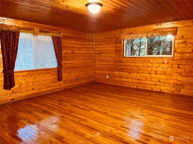 spare room with light hardwood / wood-style flooring, wood walls, and wooden ceiling