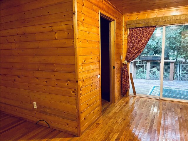 interior space featuring light wood-type flooring, a healthy amount of sunlight, wooden walls, and wooden ceiling