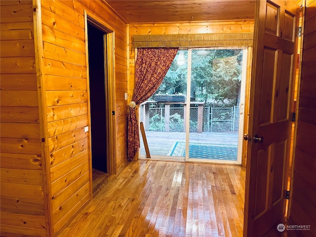 empty room with wooden walls, light hardwood / wood-style floors, and wood ceiling