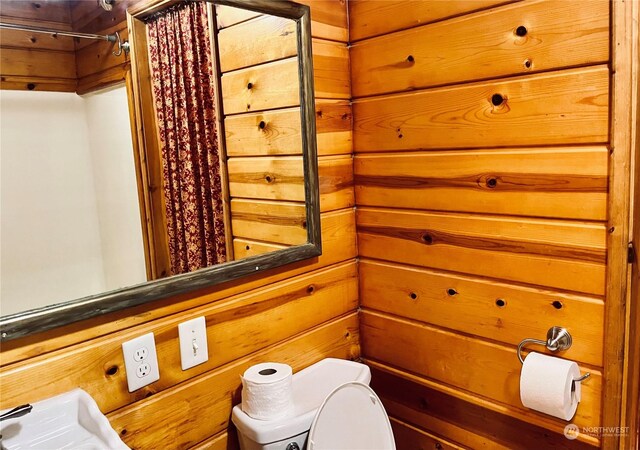 bathroom with walk in shower, wooden walls, and toilet