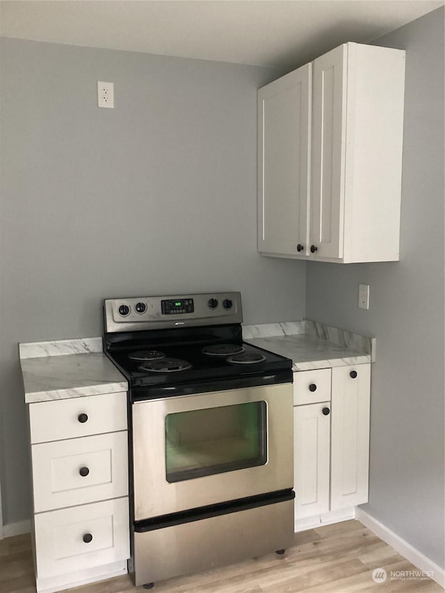 kitchen with light hardwood / wood-style floors, electric range, and white cabinets