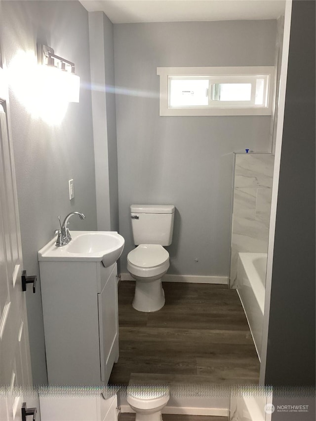 bathroom with toilet, vanity, a bathtub, and hardwood / wood-style flooring