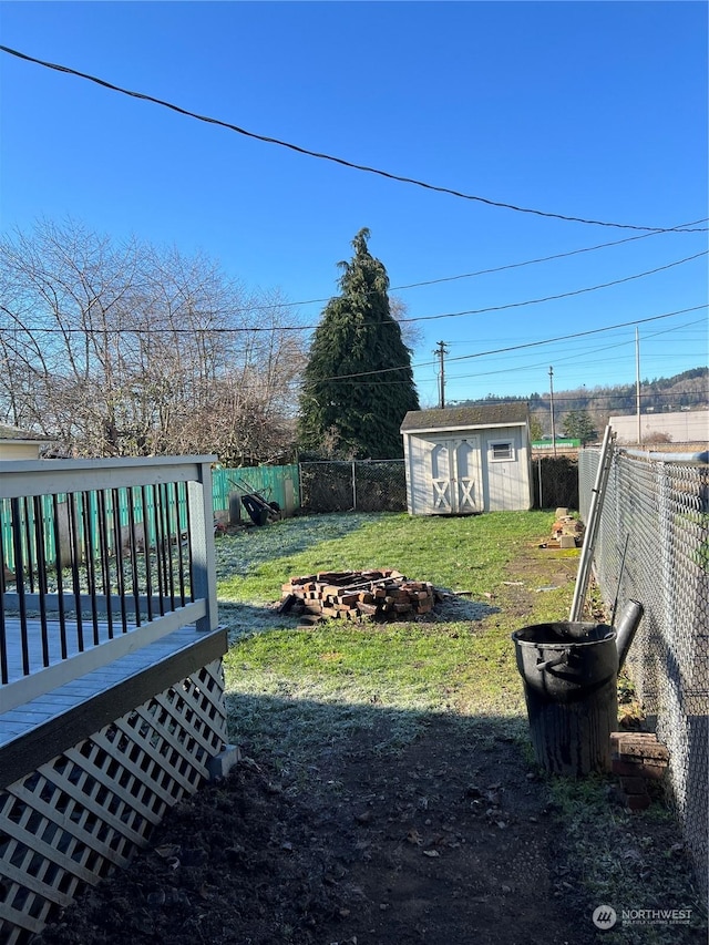 view of yard with a deck, a fire pit, and a storage unit