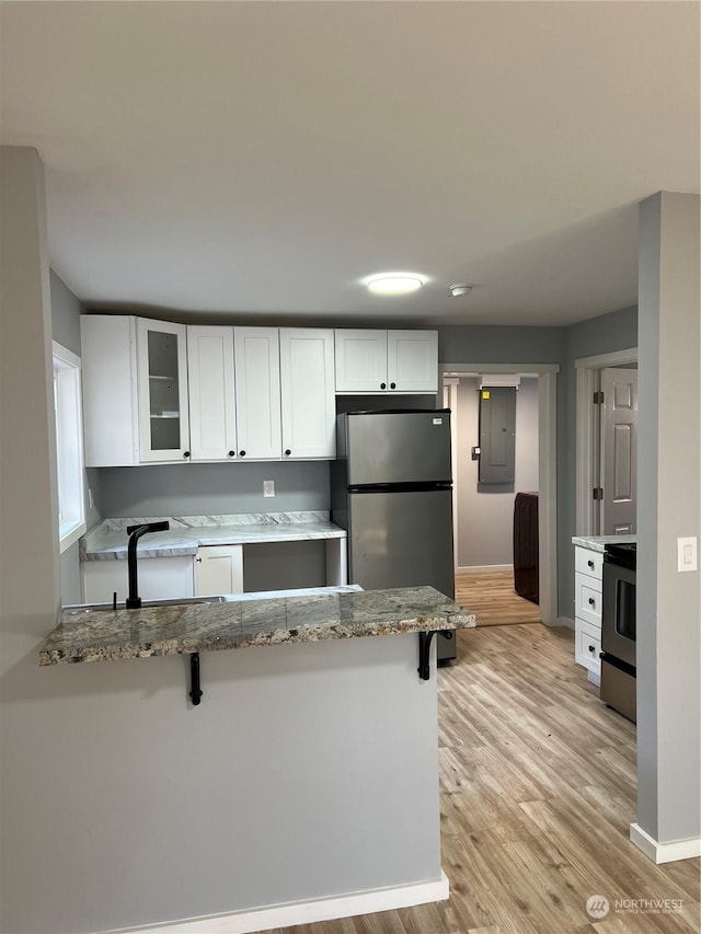 kitchen with white cabinets, kitchen peninsula, appliances with stainless steel finishes, and a breakfast bar area