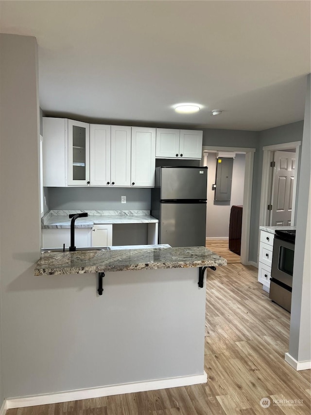 kitchen featuring white cabinets, appliances with stainless steel finishes, sink, kitchen peninsula, and a breakfast bar