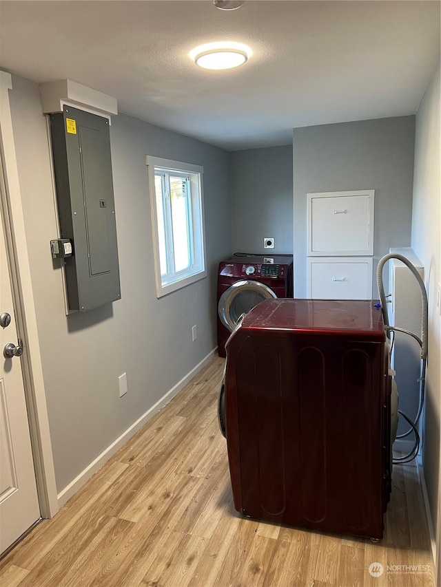 office space featuring electric panel, washer / dryer, and light hardwood / wood-style flooring