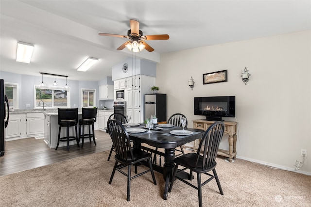 carpeted dining space featuring ceiling fan and sink