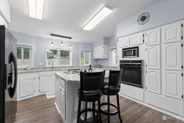 kitchen with stainless steel fridge with ice dispenser, a center island, white cabinetry, and black oven