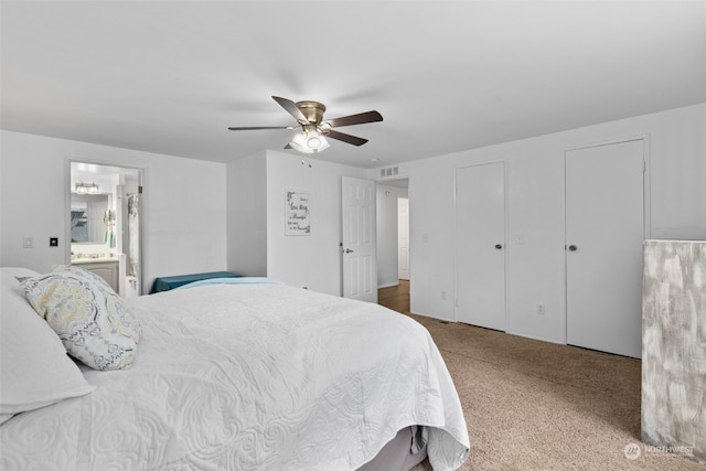 bedroom with connected bathroom, ceiling fan, carpet floors, and two closets