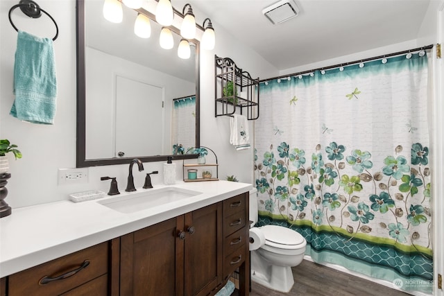 full bathroom with hardwood / wood-style flooring, vanity, shower / bath combo, and toilet