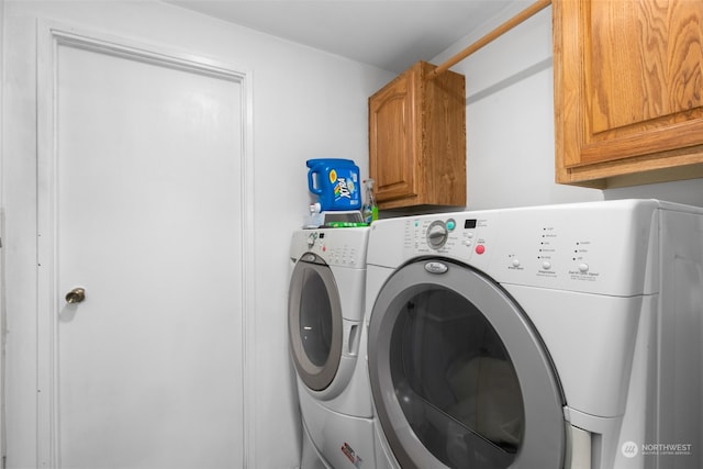 clothes washing area featuring washing machine and clothes dryer and cabinets