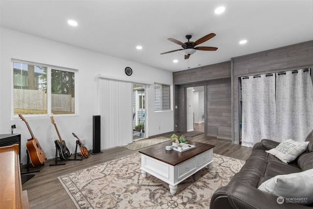 living room with ceiling fan, hardwood / wood-style floors, and wood walls