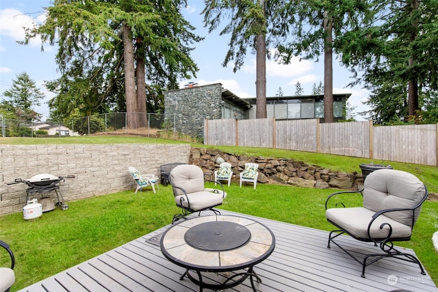 wooden terrace featuring a grill, a yard, and a fire pit