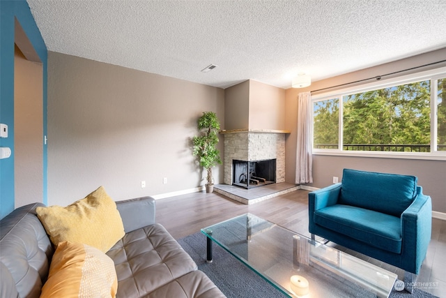 living room featuring a textured ceiling, light hardwood / wood-style floors, and a fireplace