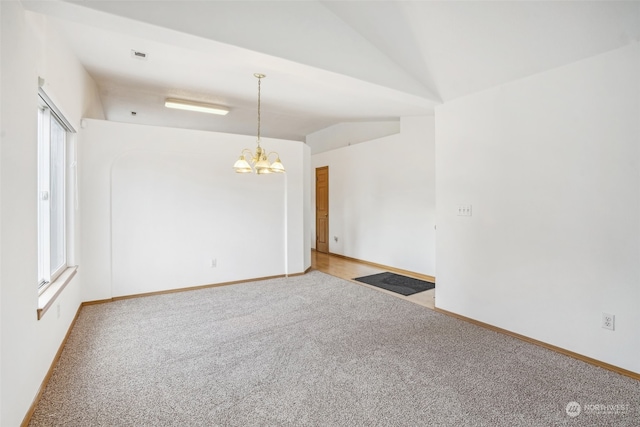 empty room featuring carpet, a chandelier, and lofted ceiling