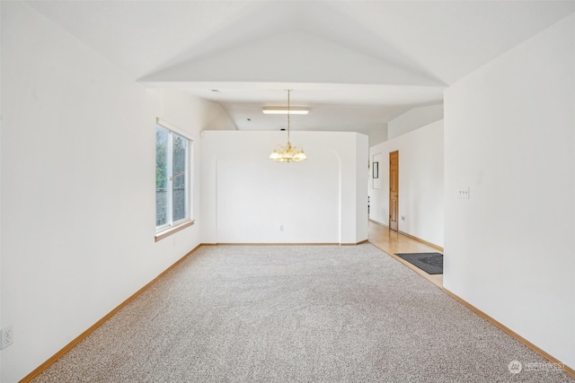 empty room featuring carpet, a notable chandelier, and vaulted ceiling