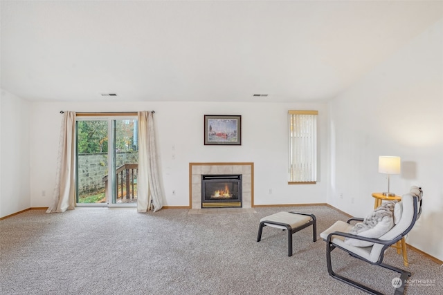 living room featuring a tiled fireplace and carpet floors