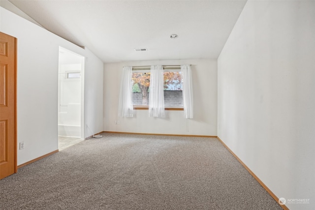 carpeted empty room with vaulted ceiling