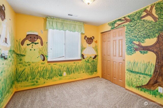 carpeted empty room featuring a textured ceiling