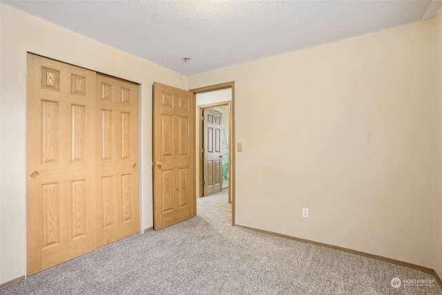 unfurnished bedroom with light carpet, a closet, and a textured ceiling