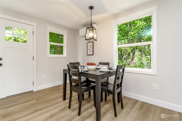 dining space with light hardwood / wood-style floors, an inviting chandelier, and a wall mounted AC