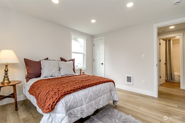 bedroom with light wood-type flooring and ensuite bath