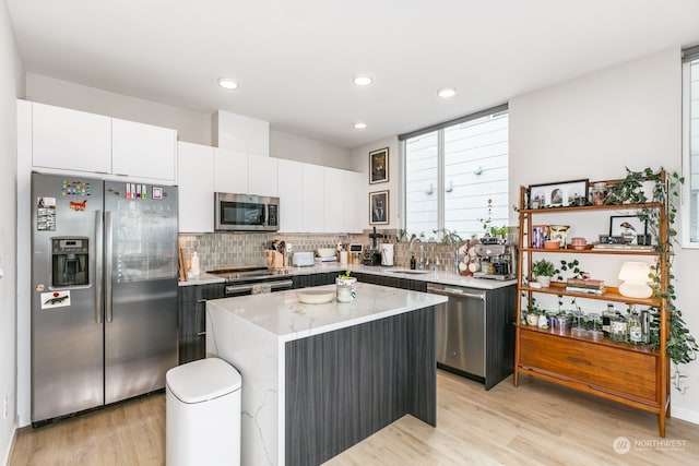 kitchen featuring sink, a kitchen island, light hardwood / wood-style flooring, white cabinetry, and stainless steel appliances