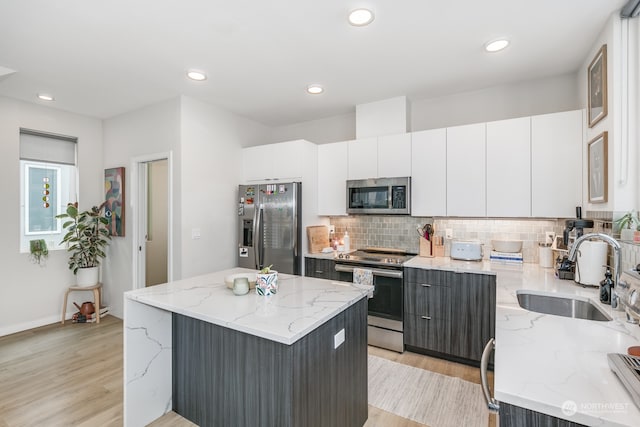 kitchen with a kitchen island, light stone countertops, and stainless steel appliances