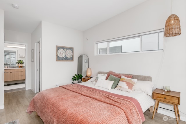 bedroom with connected bathroom and light hardwood / wood-style floors