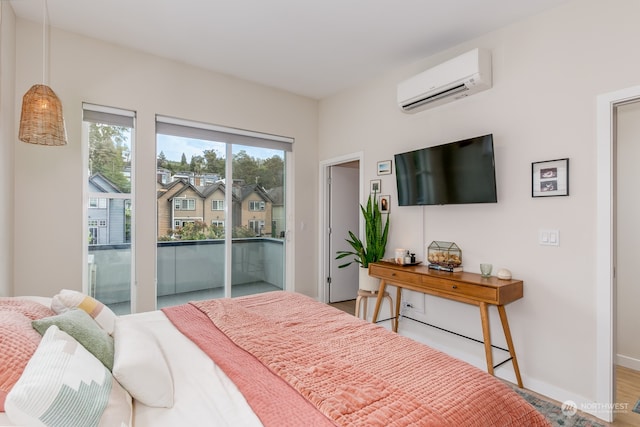 bedroom featuring access to outside, light hardwood / wood-style floors, and a wall mounted AC