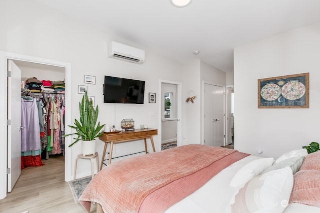 bedroom featuring light hardwood / wood-style floors, a wall mounted AC, and a closet