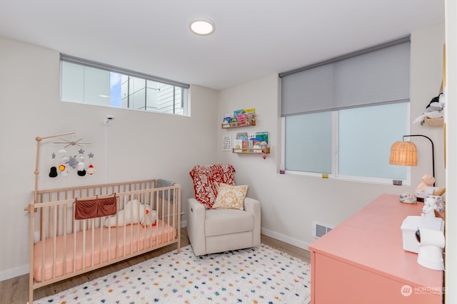 bedroom featuring a nursery area and light hardwood / wood-style flooring