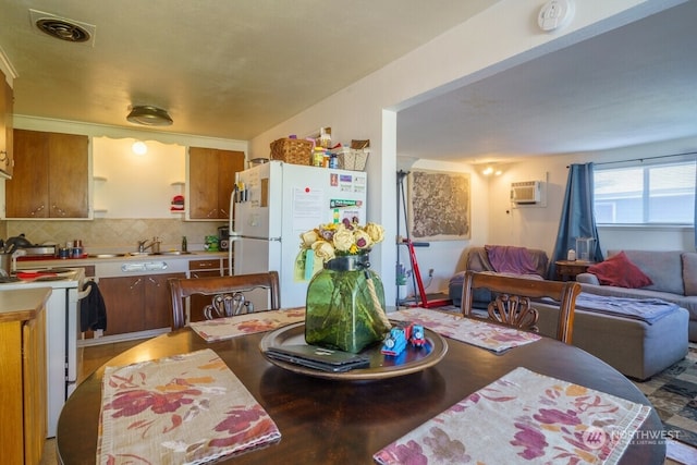 kitchen featuring hardwood / wood-style flooring, sink, an AC wall unit, white appliances, and backsplash