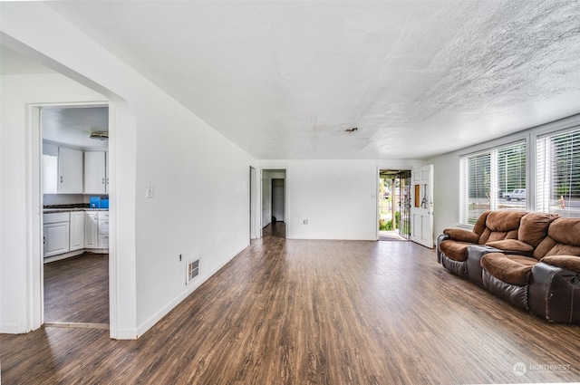 unfurnished living room featuring a textured ceiling and dark wood-type flooring