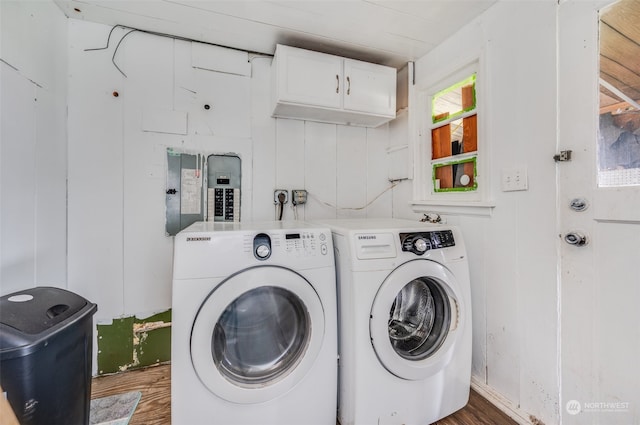 laundry room featuring dark wood-type flooring, washing machine and clothes dryer, and cabinets