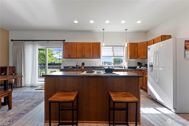 kitchen with light hardwood / wood-style floors, white fridge with ice dispenser, a kitchen bar, and plenty of natural light