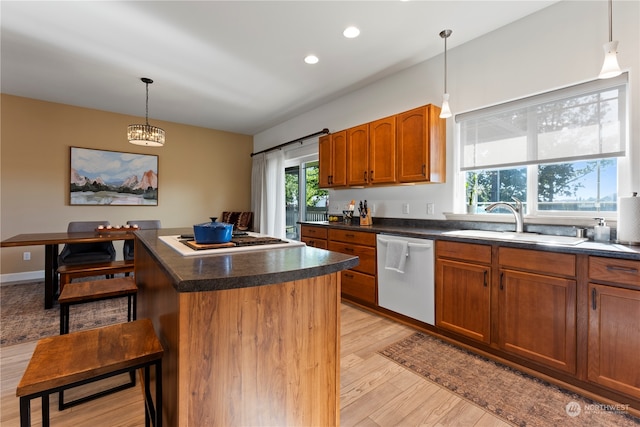 kitchen with light wood-type flooring, a center island, sink, hanging light fixtures, and white appliances