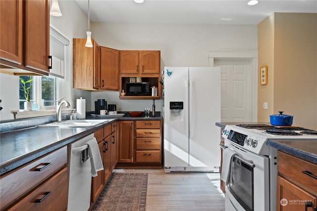 kitchen with white appliances, pendant lighting, sink, and light hardwood / wood-style flooring