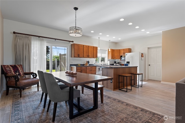 dining area featuring a notable chandelier, light hardwood / wood-style flooring, and sink