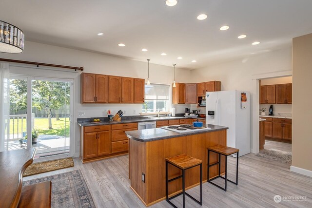 kitchen with light hardwood / wood-style flooring, a center island, a healthy amount of sunlight, and a breakfast bar area