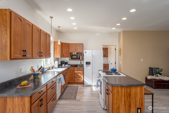 kitchen with white appliances, pendant lighting, light wood-type flooring, a kitchen bar, and sink