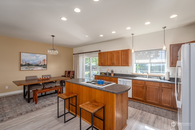 kitchen with light wood-type flooring, white appliances, a kitchen island, and plenty of natural light