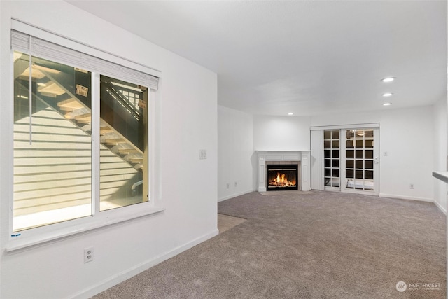 unfurnished living room featuring a tile fireplace and carpet flooring