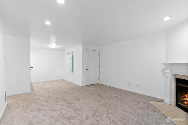 unfurnished living room featuring light colored carpet and a tile fireplace